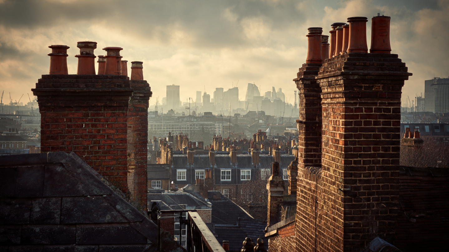 Hidden viewpoints in London from a quiet rooftop scene with historic brick chimneys in the foreground and the distant city skyline in soft afternoon light, capturing a secret rooftop viewpoint and hidden skyline perspective in London.
