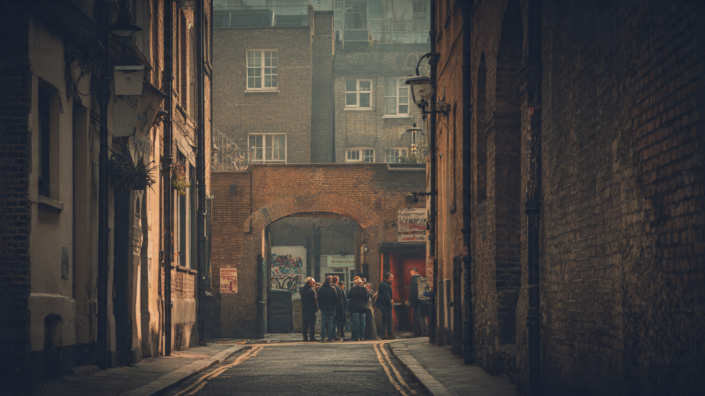 Hidden London alley with historic brick buildings and travelers exploring a quiet street, highlighting one of the best experiences in London through authentic neighborhoods, lesser-known streets, and memorable city exploration moments