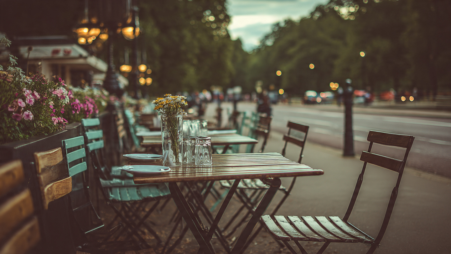 Outdoor café seating with flowers and wooden tables along a quiet street near Buckingham Palace, highlighting relaxing dining spots and scenic places to unwind as part of the best things to do near Buckingham Palace in London.