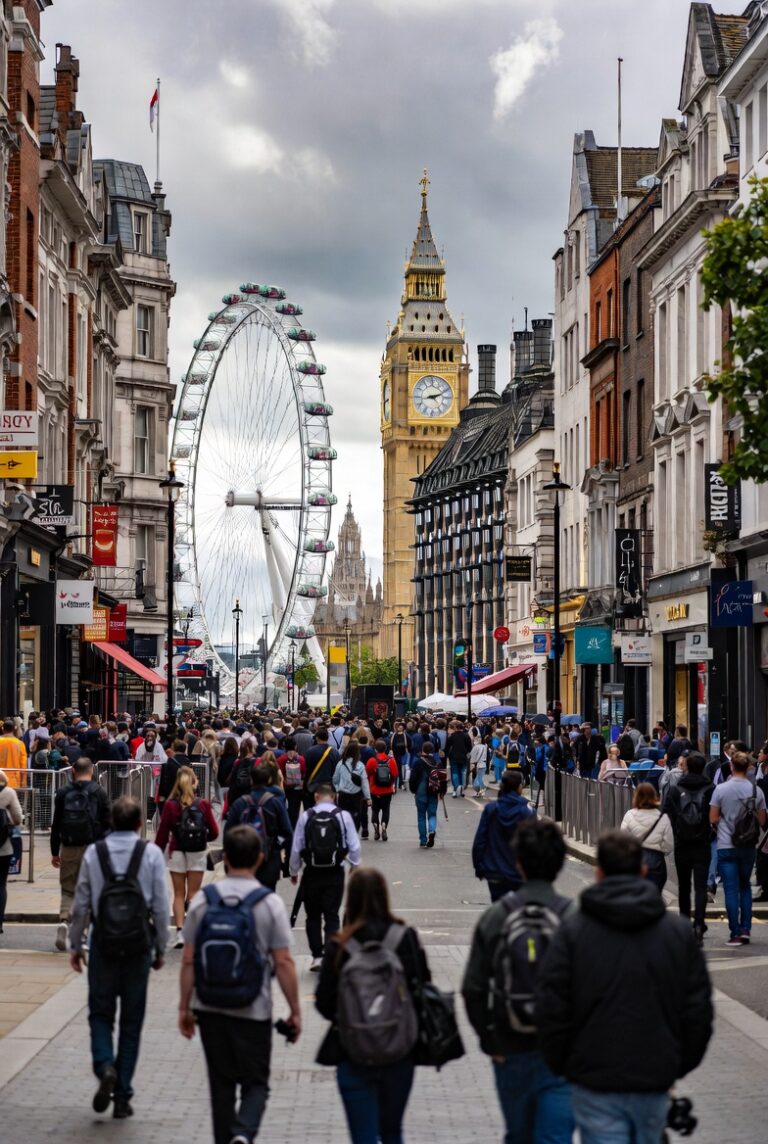 Aerial view of central London during a weekend evening with soft sunlight, lively crowds on the streets, historic buildings, and the River Thames in the background, capturing the atmosphere of a relaxed London weekend.