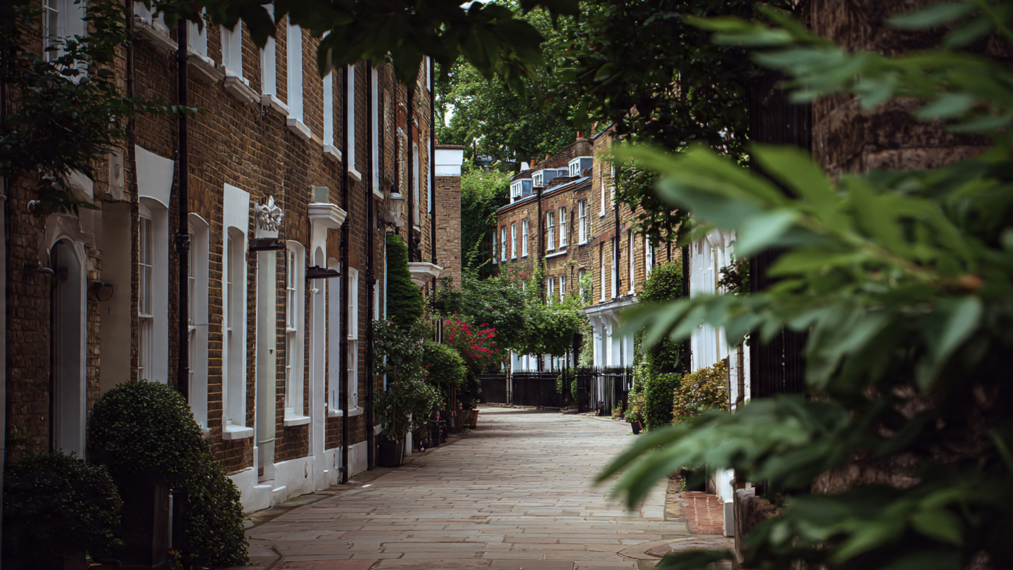 A leafy residential lane among the hidden streets in London, featuring quiet London backstreets with brick townhouses, greenery, and peaceful lesser known streets that reflect local neighborhood life away from busy roads