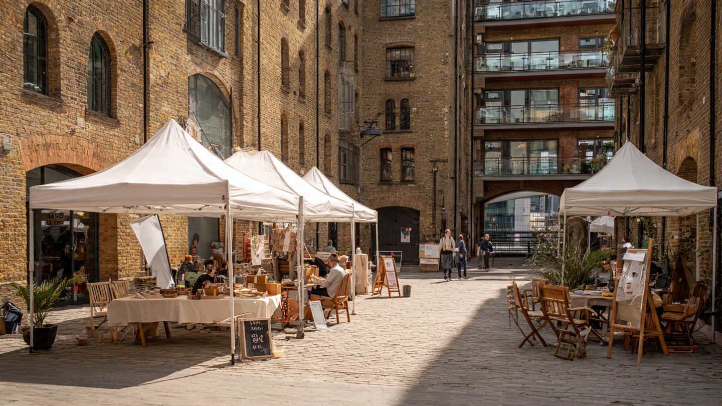 Lesser known markets in London with small pop up stalls and outdoor seating in a quiet historic courtyard, showcasing a hidden local market atmosphere in the city.