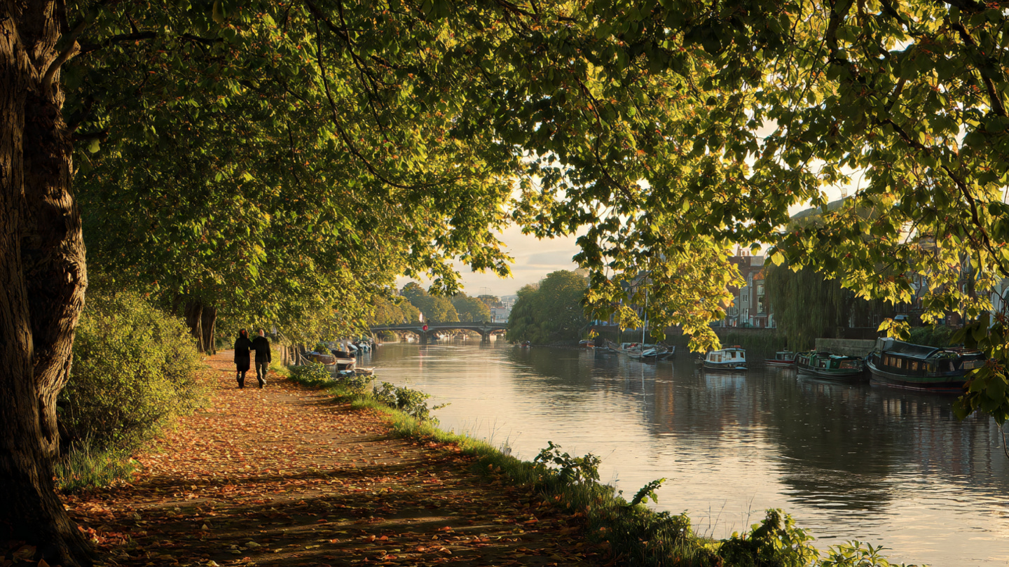 romantic walks in london along a peaceful canal path in autumn with a couple strolling beneath leafy trees and golden light