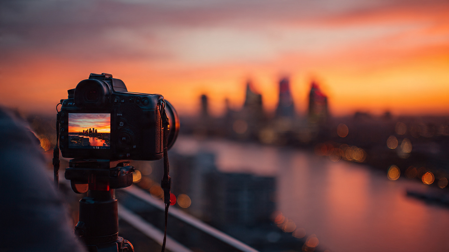 Best sunset viewpoints in London captured from a rooftop with a camera on a tripod overlooking the River Thames and glowing skyline at dusk.